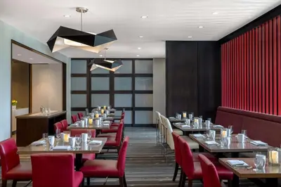 a dining room with tables and red chairs at Home2 Suites By Hilton Bristol in Bristol