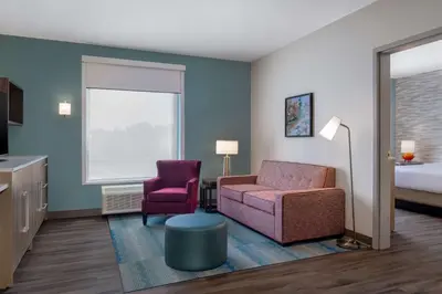 a hotel room with a bed and a couch and a chair at Home2 Suites By Hilton Bristol in Bristol