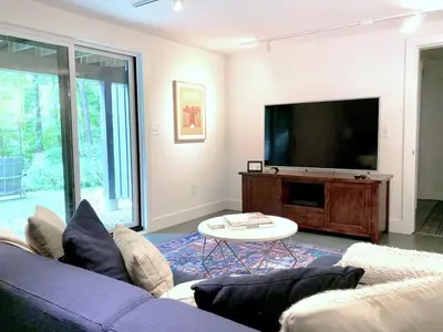a living room with a couch and a flat screen tv at Hupi House - A Peaceful Wooded Lakeside Retreat in Monterey