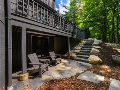 a patio with two chairs and a building at Hupi House - A Peaceful Wooded Lakeside Retreat in Monterey