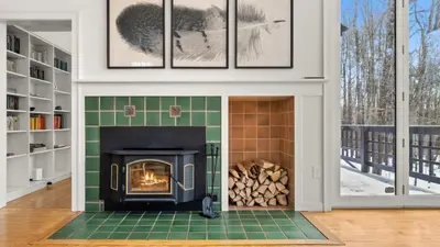 a fireplace in a living room with a stove at Hupi House - A Peaceful Wooded Lakeside Retreat in Monterey