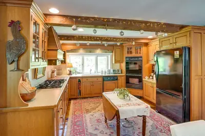 a large kitchen with wooden cabinets and a table at Family Ski Getaway 6 Mi to Berkshire East! in Hawley