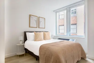 a bedroom with a bed and two windows at FiDi 1br w gym doorman wd nr Wall St NYC-983 in New York
