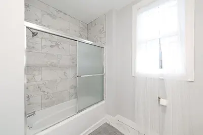a white bathroom with a shower and a window at The East Rock, 4BR, On-site Parking, Washer & Dryer, Walk to Yale in New Haven