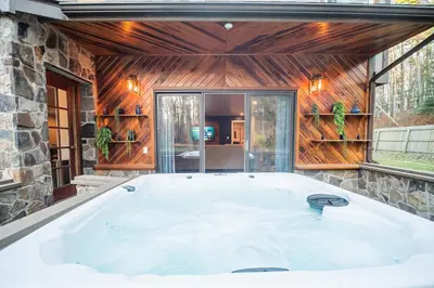 a bath tub in a room with a stone wall at 2 Houses, 22+Guests, 2 Hot Tubs, Renovated, Events Welcome! in Hawley