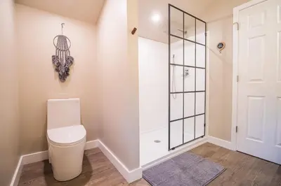 a bathroom with a toilet and a glass door at 2 Houses, 22+Guests, 2 Hot Tubs, Renovated, Events Welcome! in Hawley