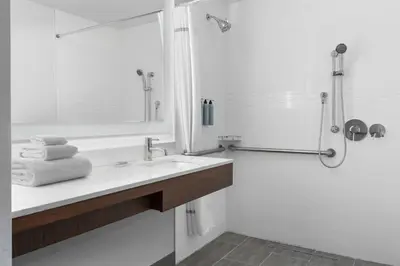 a white bathroom with a sink and a shower at Residence Inn by Marriott New York Queens in Queens