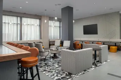 a waiting room with chairs and tables and a tv at Residence Inn by Marriott New York Queens in Queens