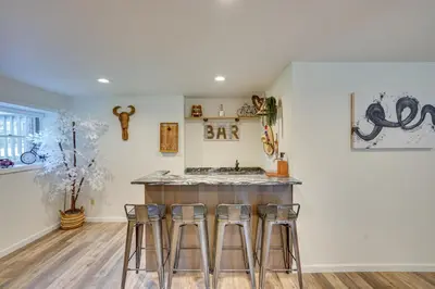 a kitchen with a bar with three stools at 6 Mi to Hunter Mtn Winter Retreat with Hot Tub! in Tannersville