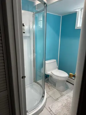 a blue bathroom with a toilet and a glass shower at Mid-Century DJs Dream near Rhinebeck in Staatsburg