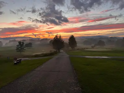 a road with a person sitting on a bench at sunset at Mid-Century DJs Dream near Rhinebeck in Staatsburg