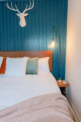 a bedroom with a bed and a blue wall at Retro Retreat renovated 2BR, desk, no chore list! in Kingston