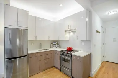 a kitchen with white cabinets and a stainless steel refrigerator at UWS 1BR w Gym WD Doorman nr Central Park NYC-377 in New York