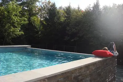 a person laying on the edge of a swimming pool at WoodHunterHome in Platte Clove