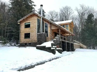 a log cabin with snow in front of it at WoodHunterHome in Platte Clove