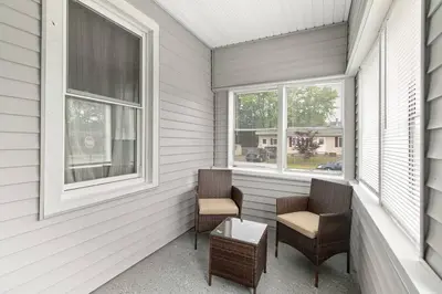 two chairs and a table on a porch with windows at Stylish, Relaxing & Comfy 3 BDR Home in Bristol