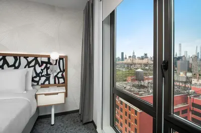 a bedroom with a bed and a view of the city at SpringHill Suites by Marriott New York Queens in Queens