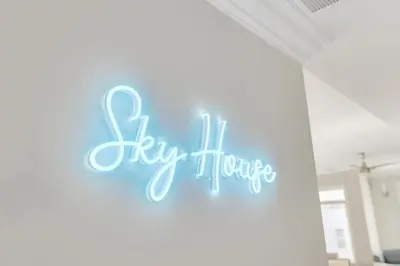 a neon sign that says fly home on a wall at SkyHouse JC - New 3BR Apt with Private Rooftop in Jersey City