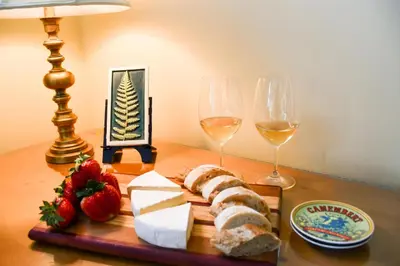 a table with a plate of cheese and two glasses of wine at Chestnut Inn at Oquaga Lake in Deposit