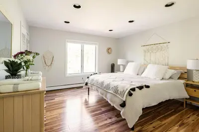 a white bedroom with a large bed and wooden floors at Modern, Cozy Hudson Valley Escape 1 Hr From NYC in Putnam Valley