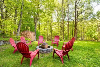 a group of red chairs sitting around a fire pit at Modern, Cozy Hudson Valley Escape 1 Hr From NYC in Putnam Valley