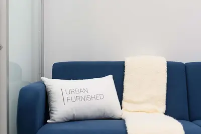 a blue couch with a pillow with the words urban furnished at 78-3C Newly renovated 1BR WD Walk 2 Central Park in New York
