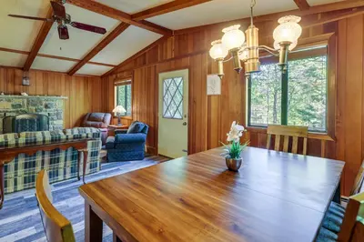 a dining room with a wooden table and a living room at Gouldsboro Vacation Rental with Pool and Lake Access! in Gouldsboro