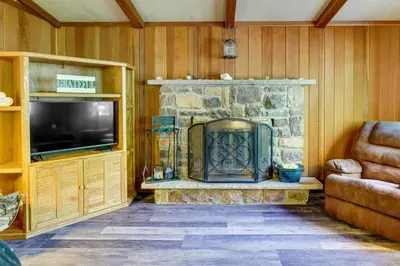a living room with a stone fireplace and a television at Gouldsboro Vacation Rental with Pool and Lake Access! in Gouldsboro