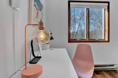 a table with a lamp and a chair in a room at Serene & Fun Family Gem ~ Big Bass Lake Community! in Gouldsboro