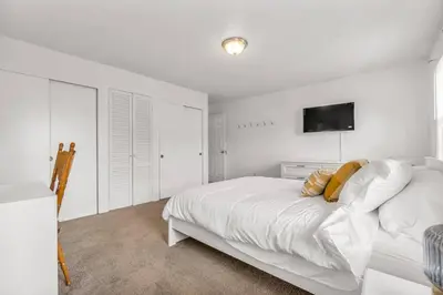 a white bedroom with a bed and a tv on the wall at North Haven Charm, 3BD Yale Retreat in North Haven