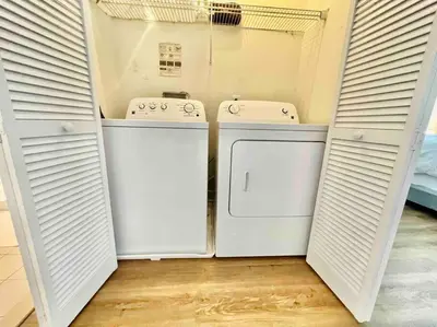 two washing machines in a laundry room with white doors at Luxury Condo Near NYC, MetLife & American Dream in Passaic