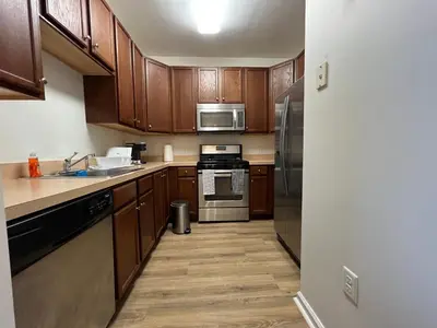 a kitchen with wooden cabinets and stainless steel appliances at Luxury Condo Near NYC, MetLife & American Dream in Passaic