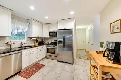 a kitchen with white cabinets and a stainless steel refrigerator at Glen Cove Vacation Rental Less Than 1 Mi to Downtown! in Glen Cove