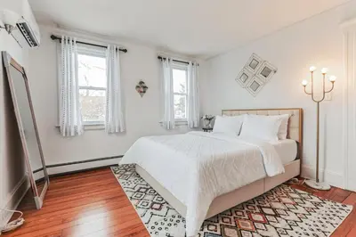 a white bedroom with a bed and two windows at Grace's Place - 3 Bedroom Townhouse in Greenwich in Greenwich