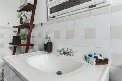 a white sink in a white tiled bathroom at Grace's Place - 3 Bedroom Townhouse in Greenwich in Greenwich