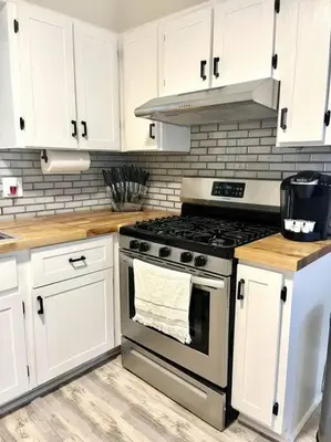 a kitchen with a stove and white cabinets at Hudson Haven in Hudson