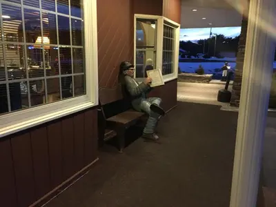 a woman sitting on a bench in a window at Landmark Motor Inn in Glens Falls