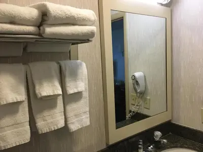 a bathroom with towels and a mirror and a sink at Landmark Motor Inn in Glens Falls