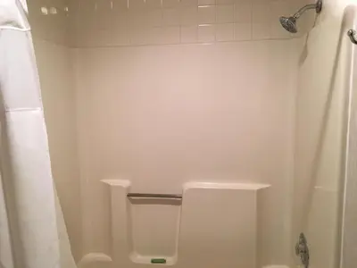 a white bathroom with a shower and a toilet at Landmark Motor Inn in Glens Falls