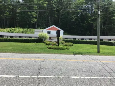 a white building with a red roof on a street at Hitching Post Motel in Cornwall