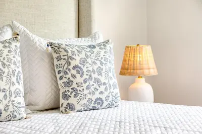 a bed with blue and white pillows and a lamp at Fairfield Cottage -Top Rated Gem, Fire Pit, Near Beach, 90 Min to NYC in Fairfield
