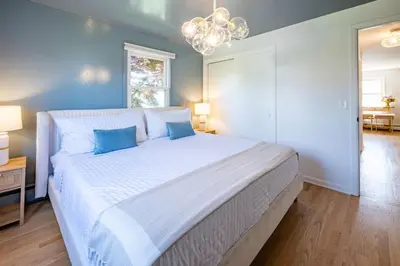 a bedroom with a large bed with blue walls and a chandelier at Fairfield Cottage -Top Rated Gem, Fire Pit, Near Beach, 90 Min to NYC in Fairfield