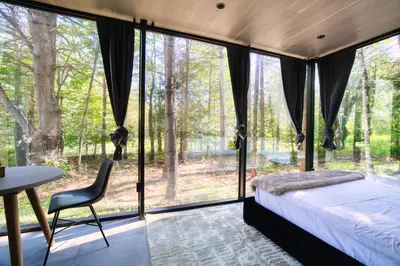 a bedroom with a bed and a table and glass windows at The Haüs Windham - Spacious Suites, Hot Tub, Mountain Views! in Windham