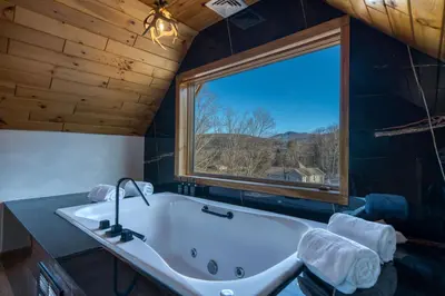a bathroom with a tub and a large window at The Haüs Windham - Spacious Suites, Hot Tub, Mountain Views! in Windham