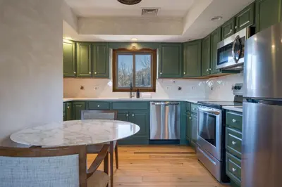 a kitchen with green cabinets and a table at The Haüs Windham - Spacious Suites, Hot Tub, Mountain Views! in Windham