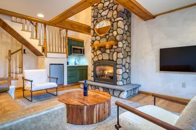 a living room with a stone fireplace and a tv at The Haüs Windham - Spacious Suites, Hot Tub, Mountain Views! in Windham