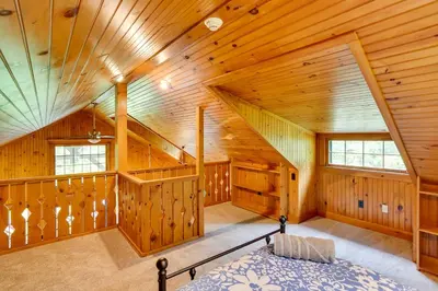 a bedroom with wooden walls and a staircase in a house at Secluded Elka Park Cabin Hot Tub and Fire Pit! in Elka Park