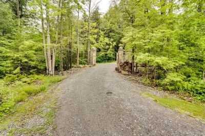 a dirt road with a gate in the woods at Secluded Elka Park Cabin Hot Tub and Fire Pit! in Elka Park