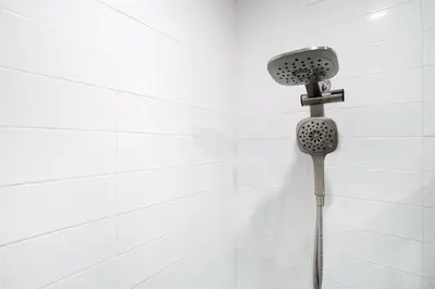 a shower head in a white tiled bathroom at 444-2C Newly renovated 1BR in Hell's Kitchen in New York