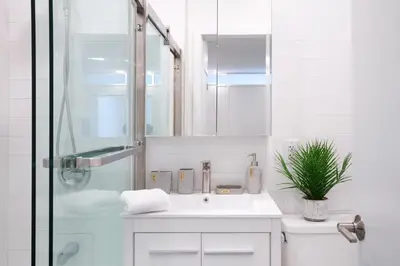 a white bathroom with a sink and a shower at 444-2C Newly renovated 1BR in Hell's Kitchen in New York